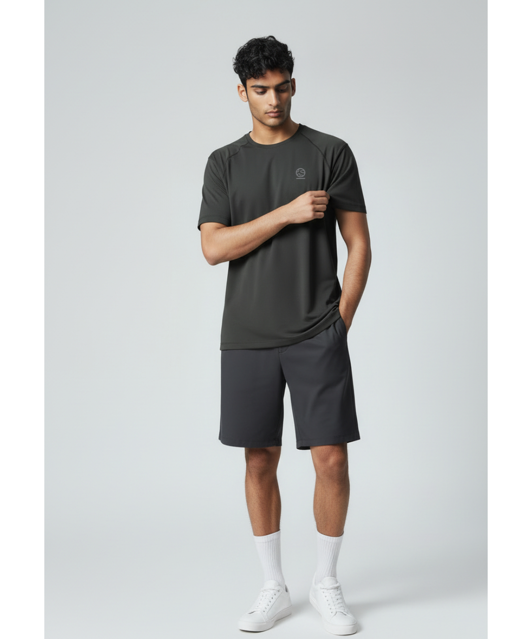 Man wearing a black underscored plastic-free t-shirt and grey shorts on a light gray background