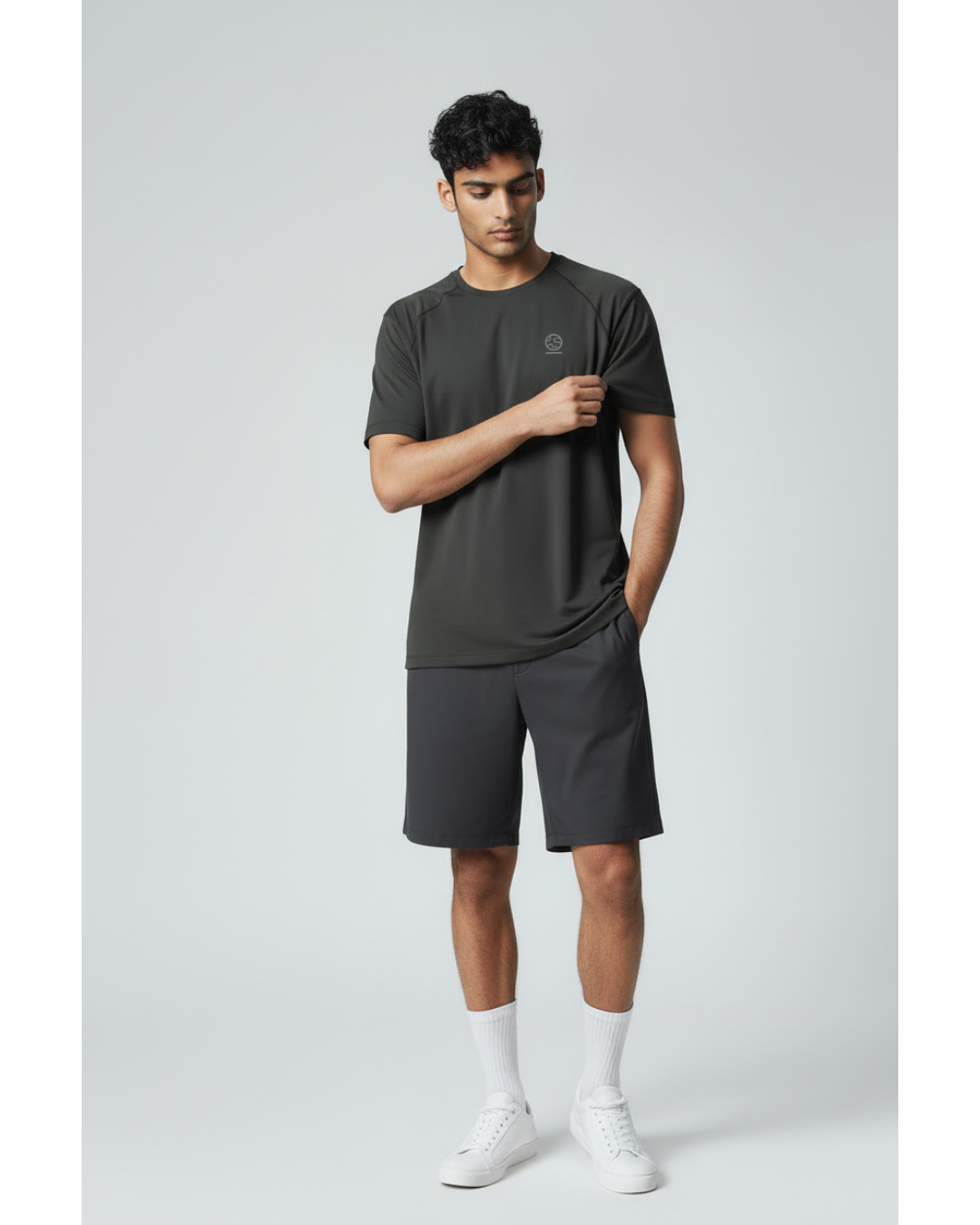 Man wearing a black underscored plastic-free t-shirt and grey shorts on a light gray background