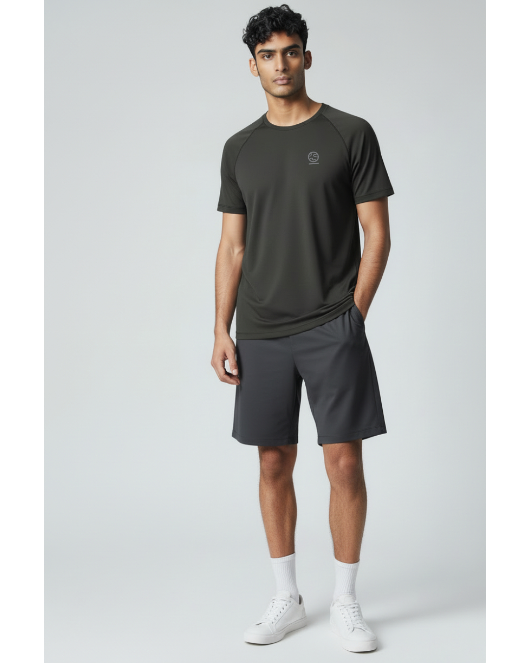 Man wearing a black underscored plastic-free t-shirt and grey shorts on a light gray background
